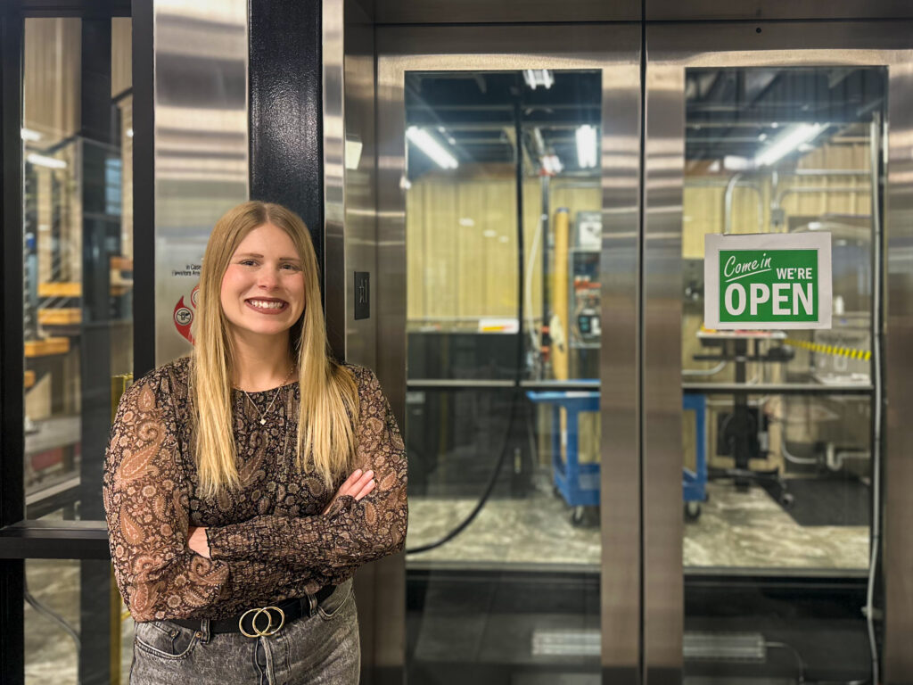 Kaelyn Rahe leans on Elevator at MEI headquarters