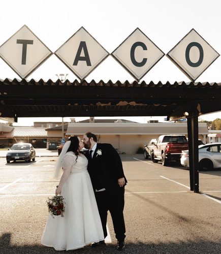 Molly and Wes kissing under the iconic retro TACO sign