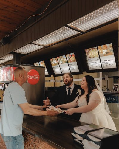 Wes and Molly Otto handing a customer their order on the day of their wedding.